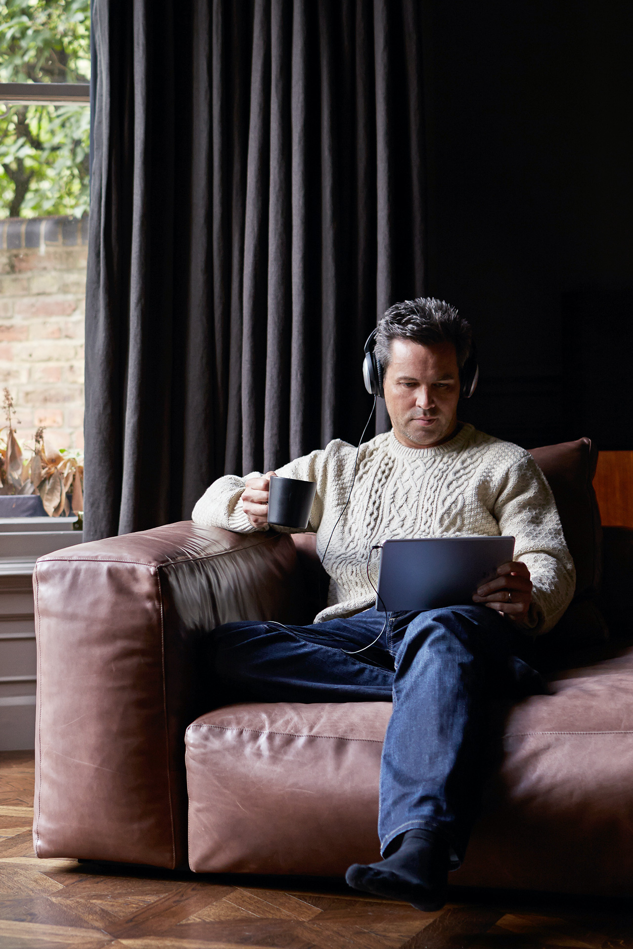 man sitting on couch looking at tablet