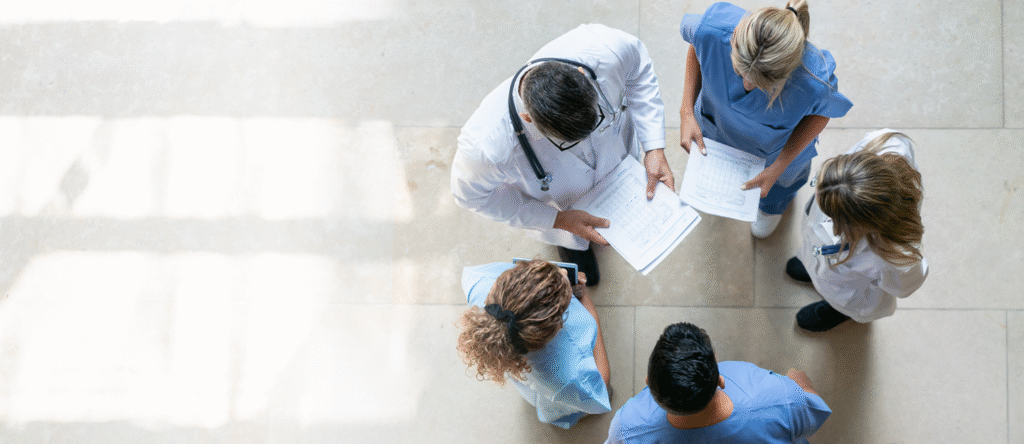 Group of healthcare professionals formed in a circle in a discussion, two are holding papers